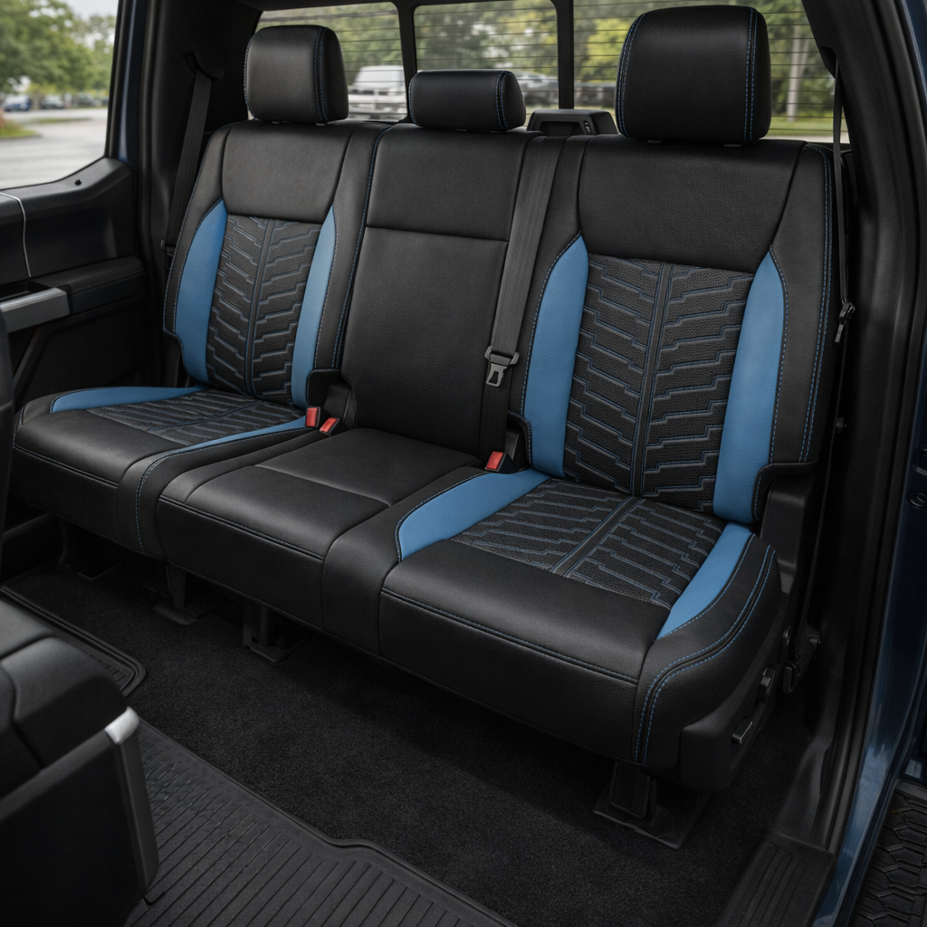 Rear in-cabin view of a 2021–2026 Ford F-250 XLT showing the Leatherteck rear bench seat in black with Bahama Blue accent panels, Bahama Blue perforated inserts with a patterned center section, and Bahama Blue contrast stitching, featuring three headrests, visible seatbelts/buckles, the rear door panel, and the rear window in the background.